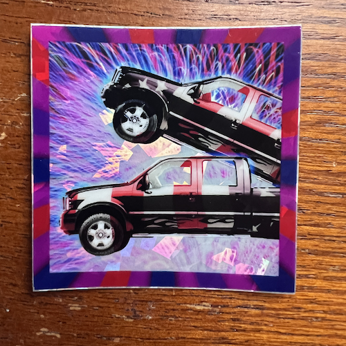 Photograph of a holographic sticker of two trucks having sex, which was the cover art for the original Two Trucks single.
